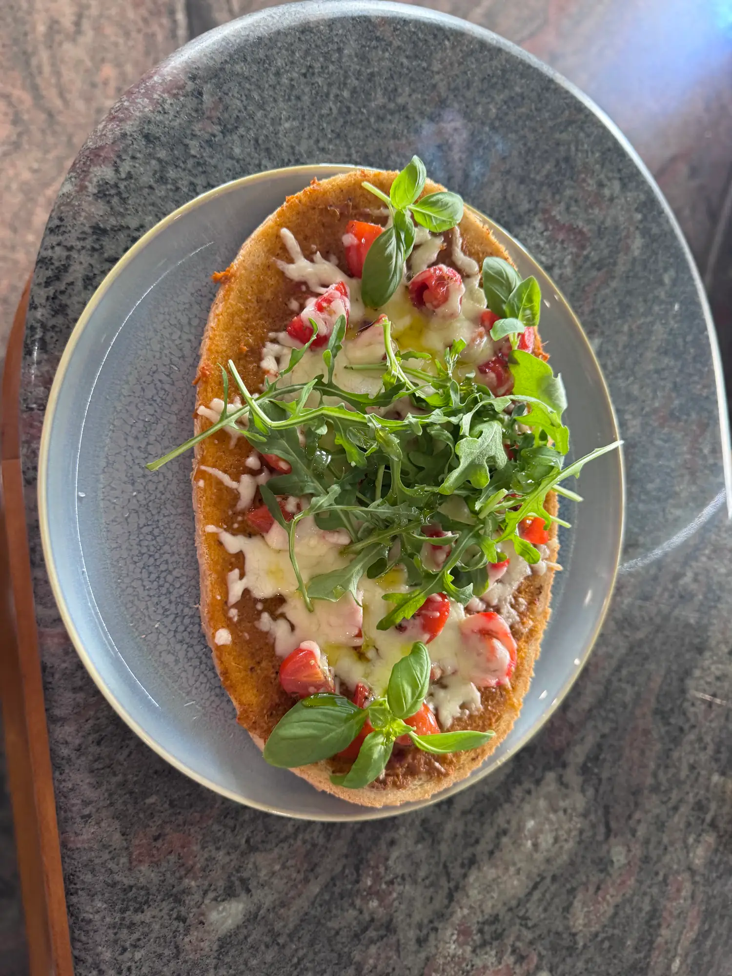 Ofenwarmes Fladenbrot mit geschmolzenem Käse, Kirschtomaten und Basilikum